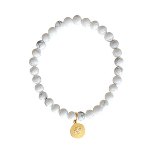 White Howlite stone stretch bracelet with gold disc charm with stamped cross.